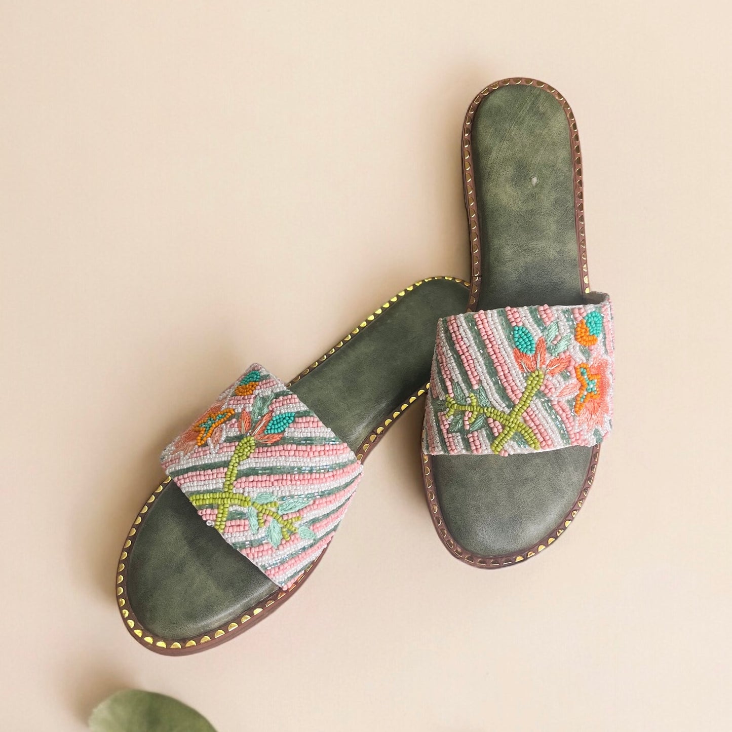 Pair of sandals with colorful patterned straps on a beige background