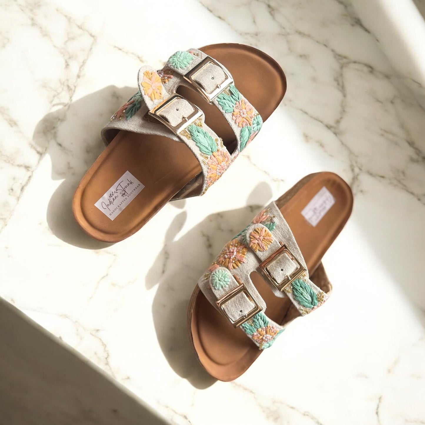 Pair of sandals with floral straps on a marble surface