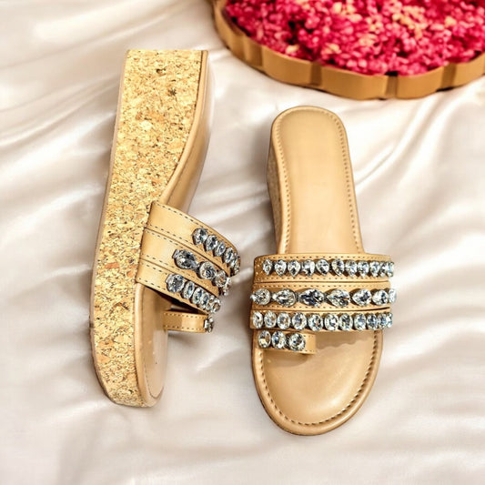 Gold sandals with rhinestone embellishments on a white fabric background