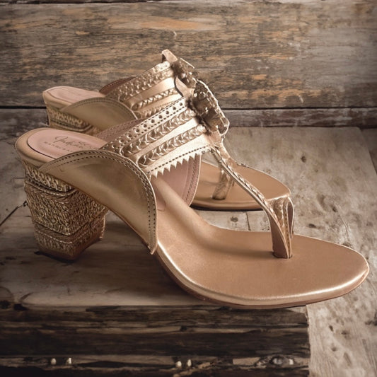 Gold sandal with embellishments on a wooden surface