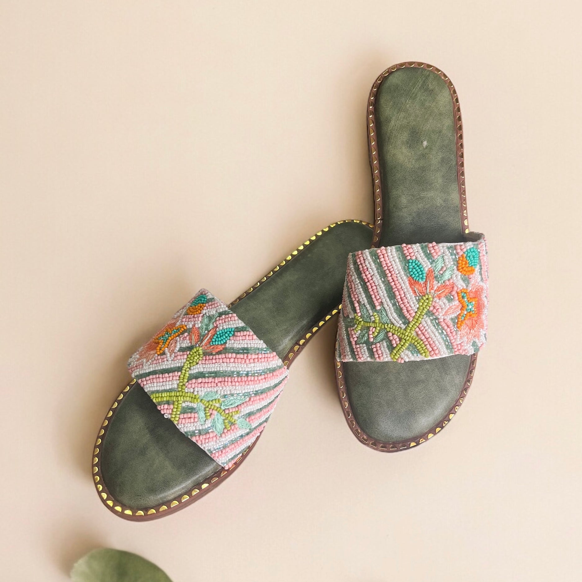 Pair of sandals with colorful patterned straps on a beige background
