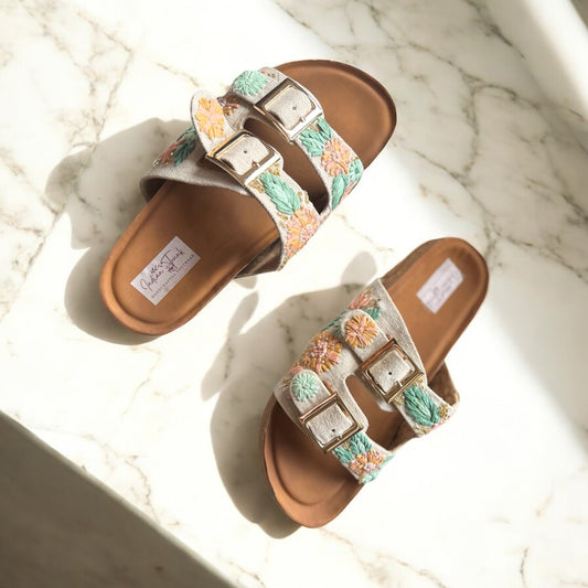 Pair of sandals with floral straps on a marble surface