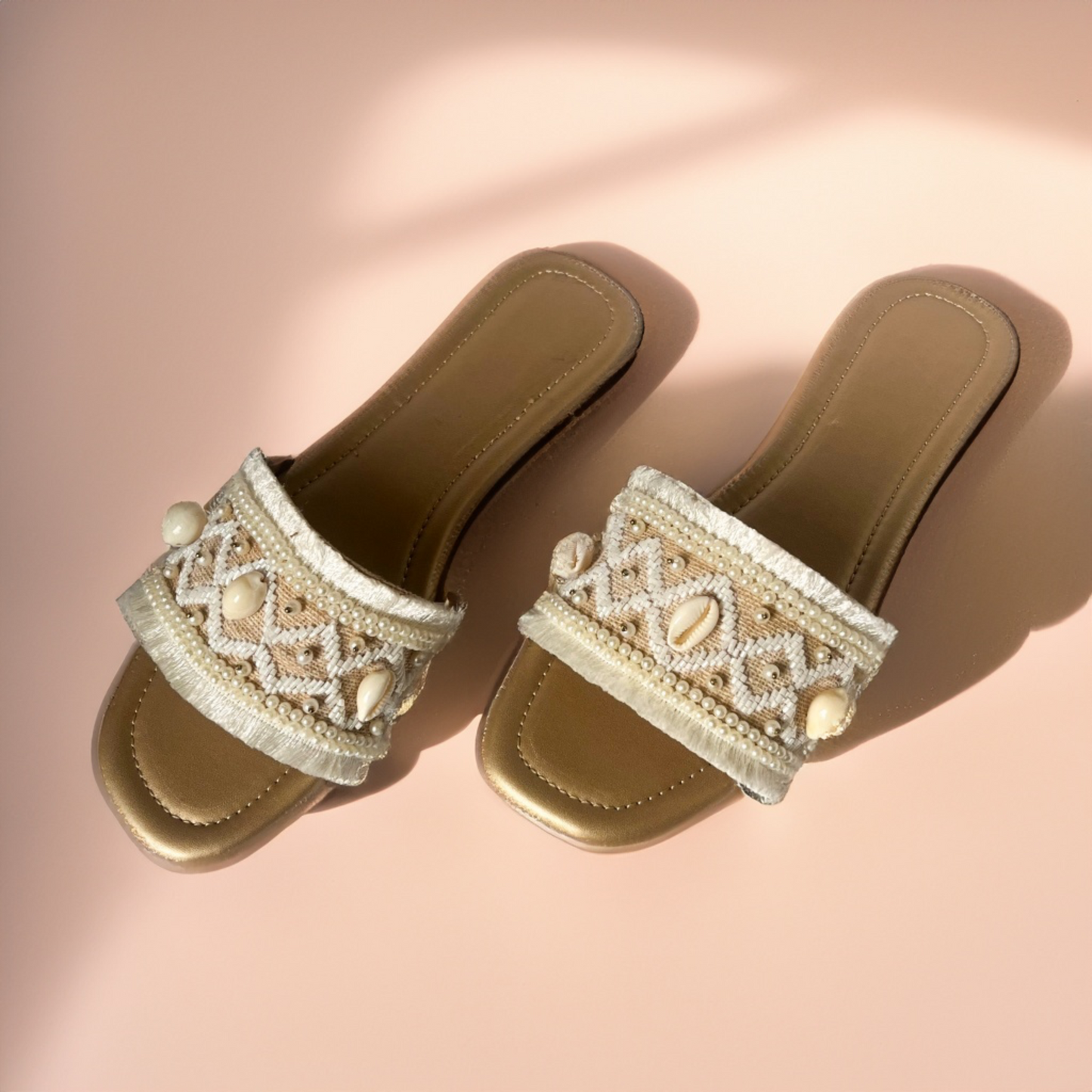 Pair of embellished sandals on a pink background